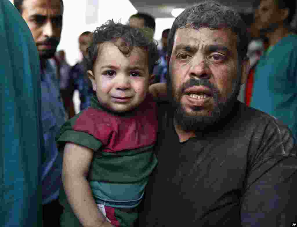 A Palestinian man carries a wounded boy to the emergency room of Shifa hospital in Gaza City, northern Gaza Strip, July 20, 2014.