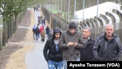 Migrants walk outside a camp in Rodgön, Germany.