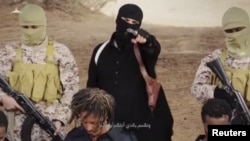 FILE - An Islamic State militant holds a gun while standing behind what are said to be Ethiopian Christians in Wilayat Fazzan, in this still image from an undated video made available on a social media website on April 19, 2015.