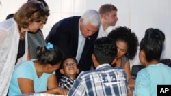 U.S. Vice President Mike Pence leans in as he visits with Venezuelan families at the Calvary Chapel in Cartagena, Colombia, Aug. 14, 2017. 