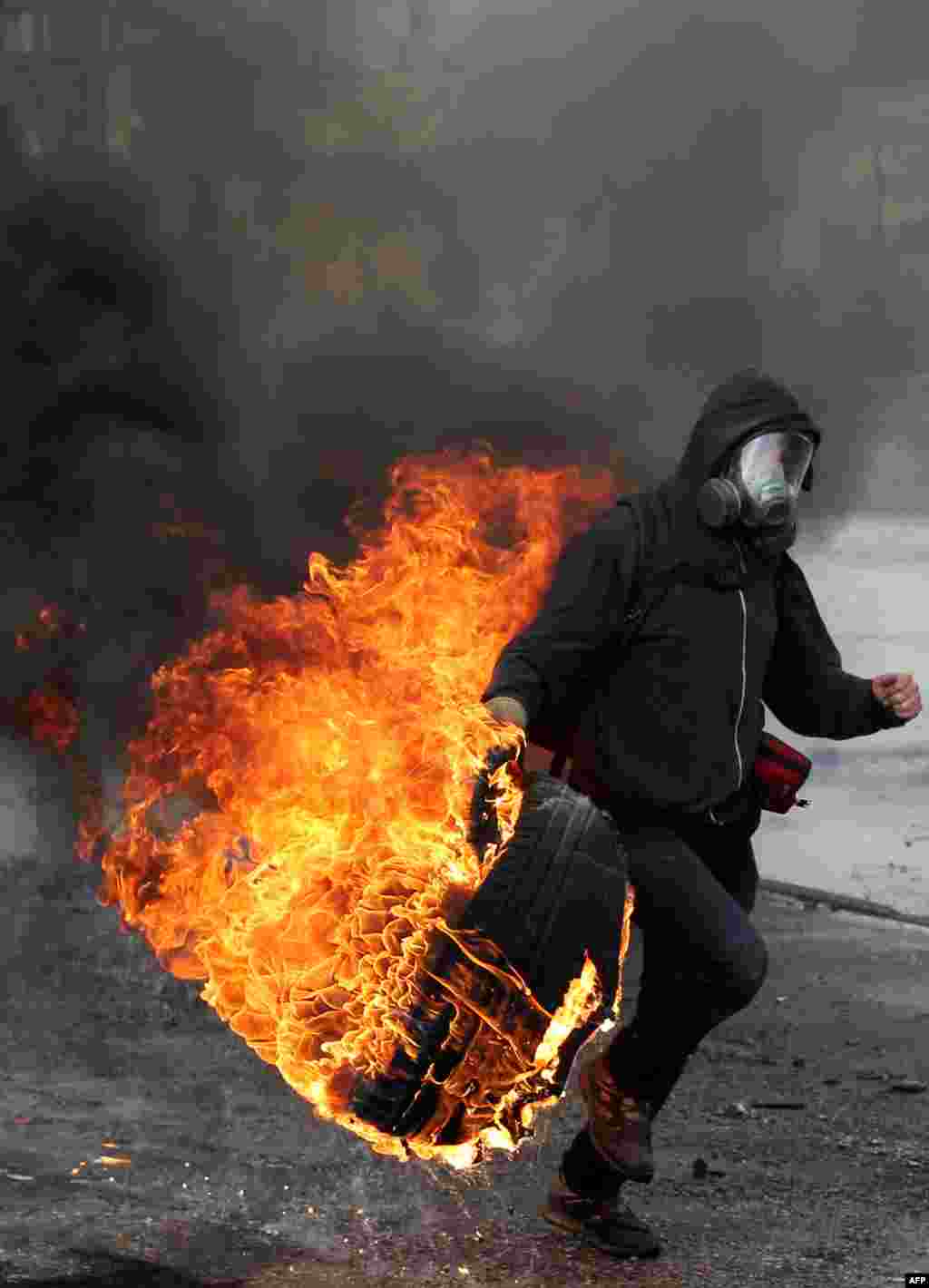 A Palestinian protestor throws a burning tire during fighting with Israeli security forces at the Qalandia checkpoint between Ramallah and Jerusalem City.