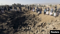 People gather around a crater cause by an airstrike in Amran province, northwest of Yemen's capital, Sana'a, April 12, 2015. 