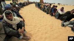 Bangladeshi evacuees wait for food at a refugee camp near the Libyan and Tunisian border crossing of Ras Jdir after fleeing unrest in Libya March 11, 2011