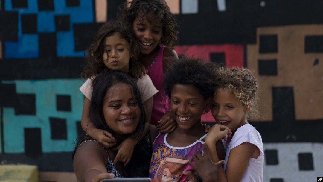 Artist Mariluce Maria de Souza takes a selfie with several children from her workshop, in front of one of her murals in the Alemao slum of Rio de Janeiro, Brazil, March 7, 2017.
