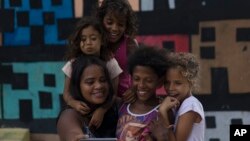 Artist Mariluce Maria de Souza takes a selfie with several children from her workshop, in front of one of her murals in the Alemao slum of Rio de Janeiro, Brazil, March 7, 2017.