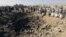 People gather around a crater cause by an airstrike in Amran province, northwest of Yemen's capital, Sana'a, April 12, 2015.  
