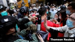 Manifestantes antigubernamentales se pelean con la policía antidisturbios durante una protesta a la hora del almuerzo mientras se lleva a cabo una segunda lectura de una controvertida ley de himnos nacionales en Hong Kong. 