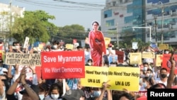 Los manifestantes portan una pancarta con ela imagen de Aung San Suu Kyi, la líder civil depuesta por el golpe militar en Rangún el 1 de febrero de 2021.