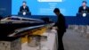 FILE - A waiter prepares for lunch next to model high speed trains and screens live broadcasting Chinese President Xi Jinping opening the Second Belt and Road Forum in Beijing, April 26, 2019.