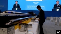 FILE - A waiter prepares for lunch next to model high speed trains and screens live broadcasting Chinese President Xi Jinping opening the Second Belt and Road Forum in Beijing, April 26, 2019.