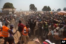 FILE - Security volunteers use sticks to fend off the crowd trying to enter a food and supplies distribution point, at a makeshift camp housing an estimated 100,000 displaced people, at Mpoko Airport, in Bangui, Central African Republic, Jan. 9, 2014.