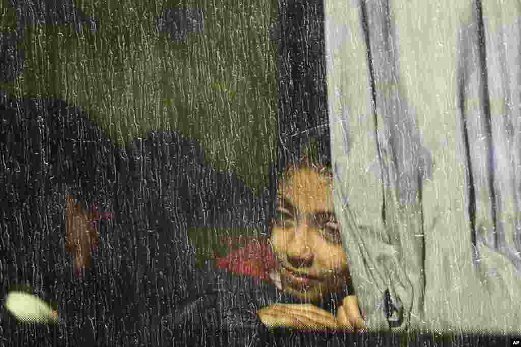 A girl looks out from a window of a bus which will transport migrants and refugees to a camp, after they were registered by authorities in Brezice, Slovenia.