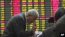 An investor gestures to another in front of the stock price monitor at a private securities company in Shanghai, China, November 22, 2012.
