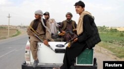 Afghan local police sitting at the back of a truck drive past a checkpoint at Chardara district, in Kunduz province, Afghanistan, June 23, 2015.