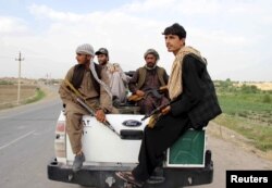 FILE - Afghan local police (ALP) sitting at the back of a truck drive past a checkpoint at Chardara district, in Kunduz province, Afghanistan, June 23, 2015.