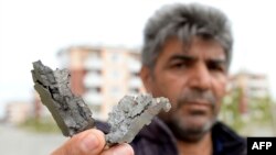 A man holds an artillery shell fragments in a district said to be damaged in recent shelling during clashes between Armenian separatists and Azerbaijan over the breakaway Nagorny Karabakh region, on the outskirts of the Azerbaijani city of Tartar