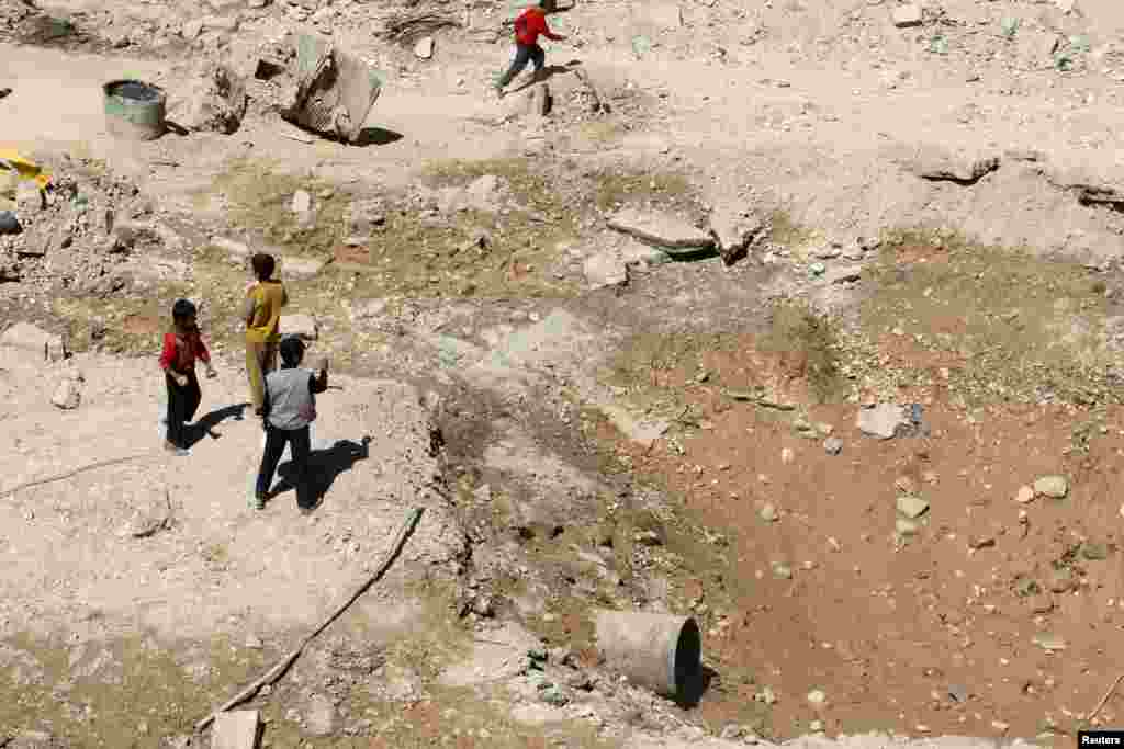 Boys stand near a crater at a damaged site in a rebel held area of Aleppo, Sept. 25, 2016.