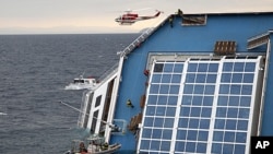 Rescue workers climb up the capsized Costa Concordia cruise ship that ran aground off the west coast of Italy at Giglio Island, January 16, 2012.