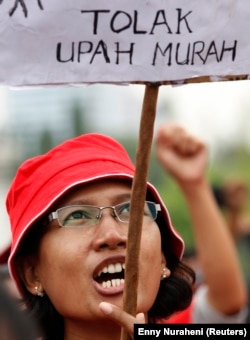 Seorang pekerja protes saat membawa tanda bertuliskan 