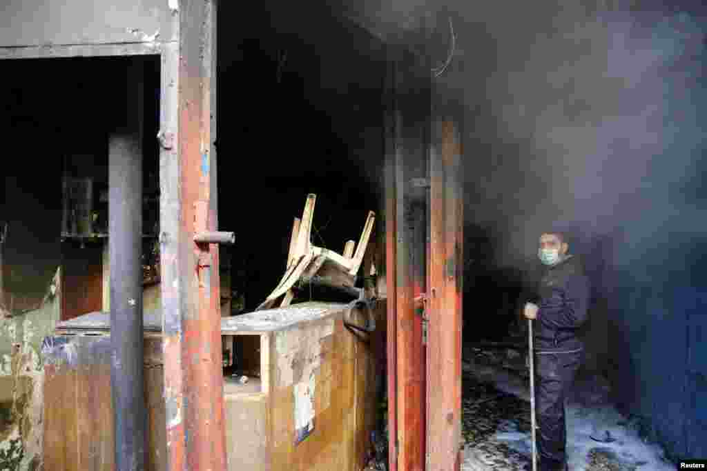 A man cleans the site of an explosion in the business district of Sinak in central Baghdad, Feb. 5, 2014. 