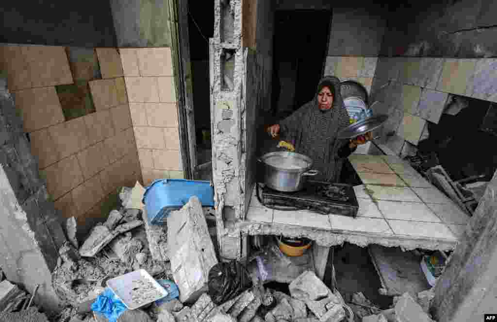 A Palestinian woman who has returned to her neighborhood cooks a meal in what remains of her home, hit by Israeli bombardment in Gaza City, after a cease-fire brokered by Egypt between Israel and Hamas.