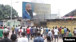 FILE - Congolese opposition supporters chant slogans as they deface a billboard featuring President Joseph Kabila during a march to press him to step down, in the Democratic Republic of Congo's capital Kinshasa, Sept. 19, 2016.