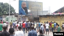 FILE - Congolese opposition supporters chant slogans as they destroy a billboard display of President Joseph Kabila, during a march to press the president to step down, in the Democratic Republic of Congo's capital Kinshasa, Sept. 19, 2016.