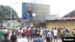 FILE - Congolese opposition supporters chant slogans as they destroy a billboard featuring President Joseph Kabila during a march calliing on Kabila to step down, in Kinshasa, DRC, Sept. 19, 2016.