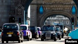 FILE - Traditional black London cabs are seen driving across the British capital's Tower Bridge July 23, 2012.
