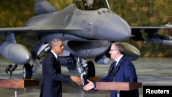With an F-16 fighter in the background, U.S. President Barack Obama and Poland's President Bronislaw Komorowski (R) shake hands upon Obama's arrival at Chopin Airport in Warsaw, June 3, 2014.