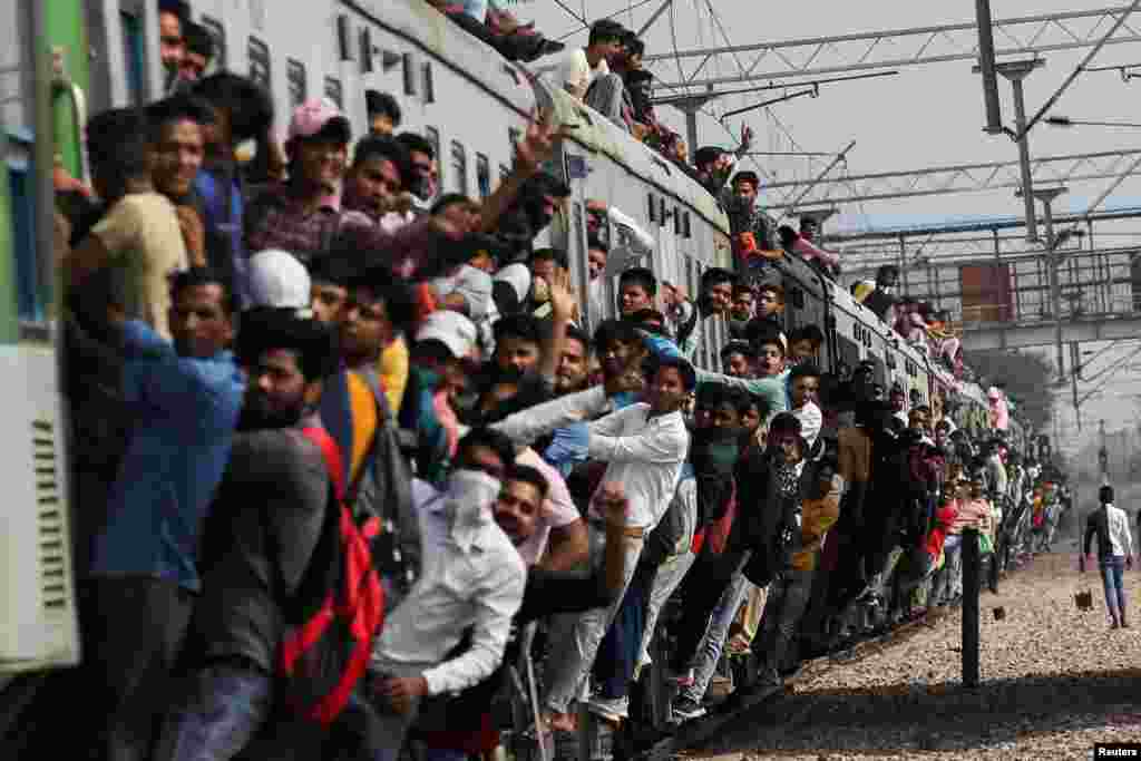 People cling on to a crowded train during the ongoing COVID-19 outbreak in Ghaziabad, India.