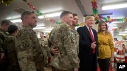 El presidente Donald Trump y la primera dama Melania Trump posan para una fotografía mientras visitan a los militares en un comedor en la base aérea de Al Asad, Irak, el miércoles 26 de diciembre de 2018.