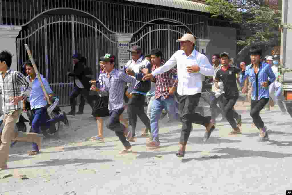 Cambodian garment workers run as they escape for safety in front of a factory of Yak Jin in Kambol village on the outskirts of Phnom Penh, Cambodia, Thursday, Jan. 2, 2014.