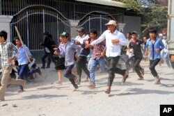 Cambodian garment workers run as they escape for safety in front of a factory of Yak Jin in Kambol village on the outskirts of Phnom Penh, Cambodia, Thursday, Jan. 2, 2014.