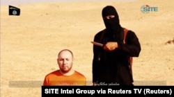 FILE - A masked, black-clad militant, identified by The Washington Post newspaper as a Briton named Mohammed Emwazi, stands next to a man purported to be Steven Sotloff in this still image from a video obtained from SITE Intel Group website, Feb. 26, 2015