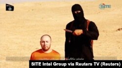 FILE - A masked, black-clad militant, identified by The Washington Post newspaper as a Briton named Mohammed Emwazi, stands next to a man purported to be Steven Sotloff in this still image from a video obtained from SITE Intel Group website, Feb. 26, 2015