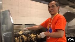 Satriyo Utomo alias Nanang, ketua tim relawan dapur Muktamar IMSA 2019, menggoreng ikan filet di dapur (VOA/Karlina).
