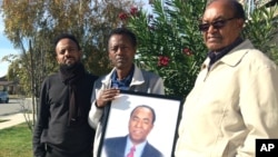Family members from left, Fobel Tekleab, Fessehatsion Gebreselassie and Abraham Amanios, hold a photo of Isaac Amanios, Dec. 5, 2015.