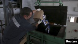 An employee throws sliced and packed meat into a furnace during the destruction of illegally imported food at a customs house at Pulkovo Airport in St. Petersburg, Russia, Aug. 6, 2015.