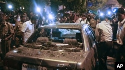 Plain clothed police surround a vehicle which was damaged at the site of an explosion in the Dadar area of Mumbai. Three explosions rocked crowded districts of India's financial capital of Mumbai during rush hour on Wednesday, killing at least eight peopl