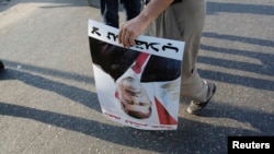 18일, 이집트 수도 카이로에서 벌어진 시위에서 한 반정부 시위자가 축출된 무함마드 무르시 전 대통령의 포스터를 들고 있다.