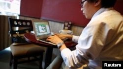 Seorang pria tengah bekerja dengan komputernya di dalam sebuah kedai kopi di pusat kota Shanghai, 25 September 2013 (Foto: dok). Pemerintah China minggu ini mengeluarkan peraturan baru, yang mengharuskan para pembat film untuk mendaftarkan nama dan menyerahkan produksi mereka untuk diperiksa sebelum mengunggahnya ke internet.