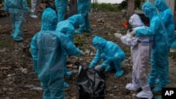 A woman in white personnel protective equipment reacts as she gets a glimpse of her husband's body, a victim of COVID-19, in Gauhati, India, Sept. 10, 2020. 