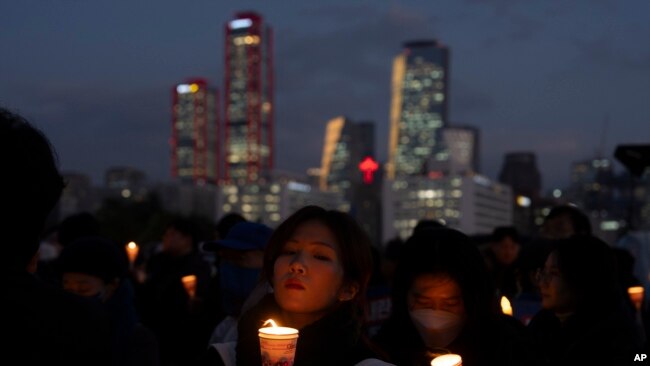 Orang-orang menyalakan lilin sebagai protes terhadap Presiden Korea Selatan Yoon Suk Yeol di Seoul, Korea Selatan, Kamis, 5 Desember 2024. (Foto: Ng Han Guan/AP Photo)