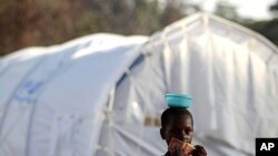 An Ivorian girl holds a 10 Liberian dollar banknote as she goes to buy food for her family in a camp housing more than 2,600 Ivorian refugees, with more arriving daily, in Solo Town, Liberia, May 25, 2011.