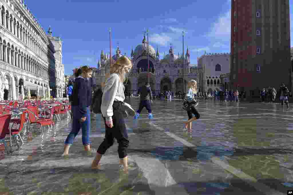 Orang-orang berjalan di Lapangan San Marco yang populer bagi wisatawan dan tergenang banjir di Venesia, Italia (5/11), meningkatkan kekhawatiran akan dampak buruk perubahan iklim (Foto: AP).&nbsp;