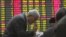 An investor gestures to another in front of the stock price monitor at a private securities company in Shanghai, China, November 22, 2012.