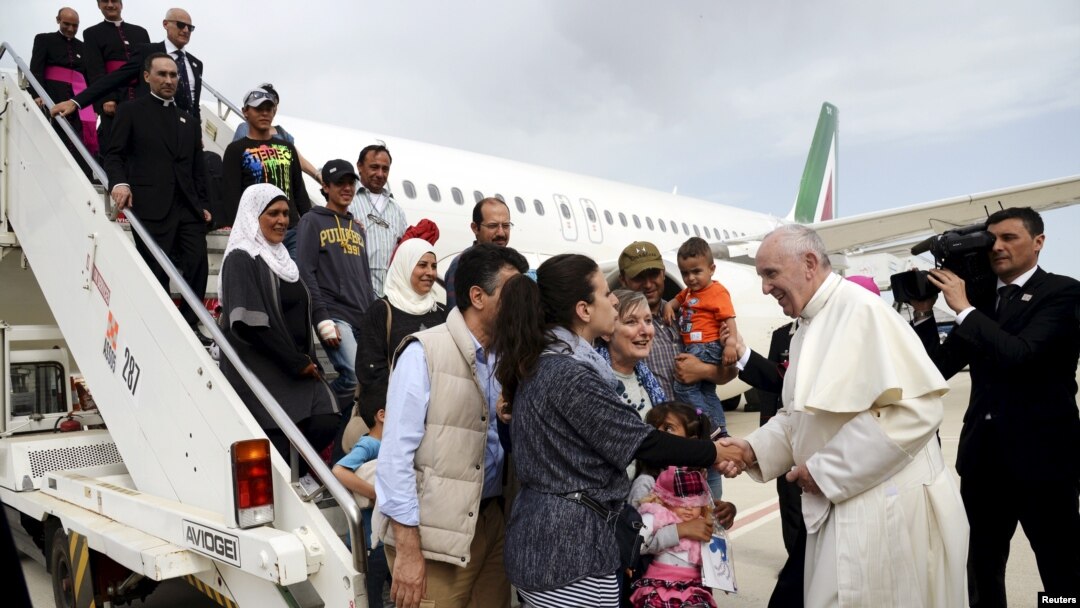 Paus Fransiskus menyambut sekelompok pengungsi Suriah setelah mendarat di bandar udara Ciampino di Roma setelah mengunjungi kamp pengungsi Moria di pulau Lesbos, Yunani (16/4). (Reuters/Filippo Monteforte)