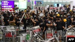FILE - Pro-democracy protesters block the entrance to the airport terminals after a scuffle with police at Hong Kong's international airport, Aug. 13, 2019. Hundreds of flights were canceled that day as pro-democracy protesters staged a sit-in.