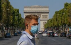 A man wearing a masks to prevent the spread of COVID-19 crosses the Champs Elysees avenue in Paris, Aug 9, 2020.